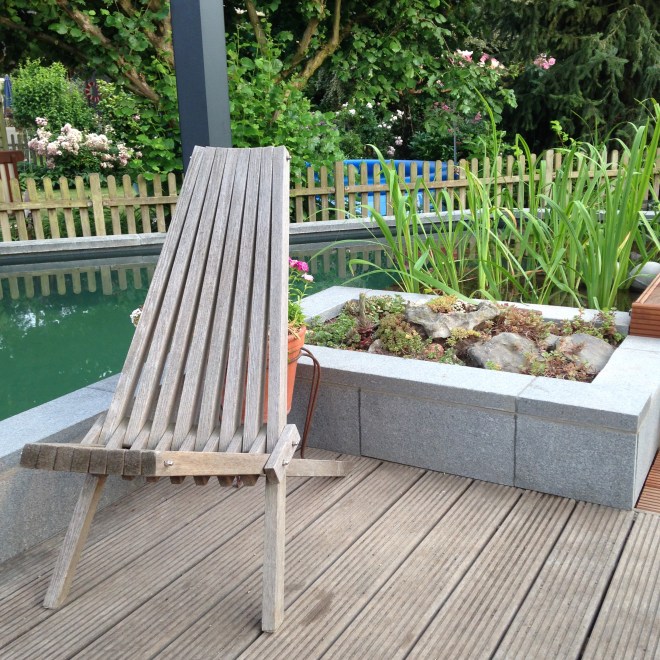 Zwemvijver op de achtergrond, stoel om op op te drogen op de voorgrond. Zomerse zaligheid.